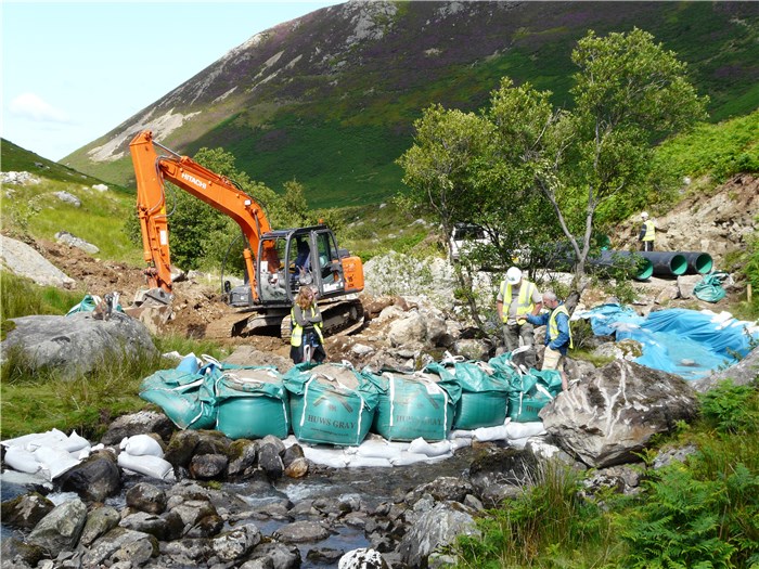 The river is diverted allowing the digger to install pipes on the south bank to carry the river while the weir is built 15 July 2015