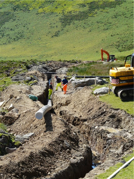 The penultimate section of pipe below the weir is eased into its trench 23 June 2015 The penultimate section of pipe below the weir is eased into its trench 23 June 2015