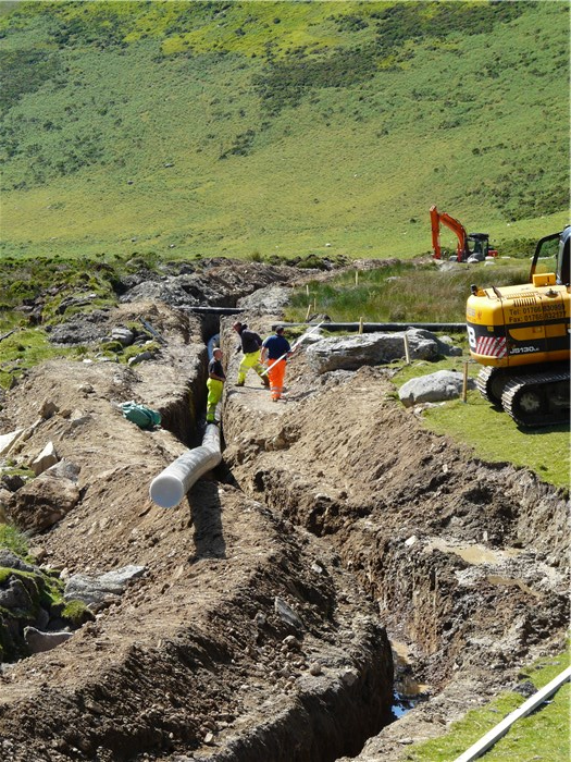 The penultimate section of pipe below the weir is eased into its trench 23 June 2015